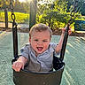 toddler, child, swing, playground, sunset, smiling, happy, outdoor, curly_hair, sunlight, park, chains, seat, greenery, leaves, fence, shadow, casual_clothing, joy, playtime