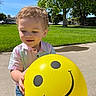 Nikolai joined the competition — help win amazing prizes! child, toddler, balloon, yellow_balloon, smiley_face, curly_hair, outdoor, daylight, green_grass, trees, sidewalk, casual_clothing, short_sleeves, jeans, happy, playful, person, sunny, park, nature