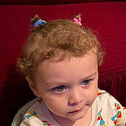 Nikolai joined the competition — help win amazing prizes! toddler, child, face, hair_ties, curly_hair, colorful_clothing, patterned_shirt, indoor, portrait, looking_away, expression, cute, young_child, person, sitting, closeup, red_background, soft_lighting, casual, innocent