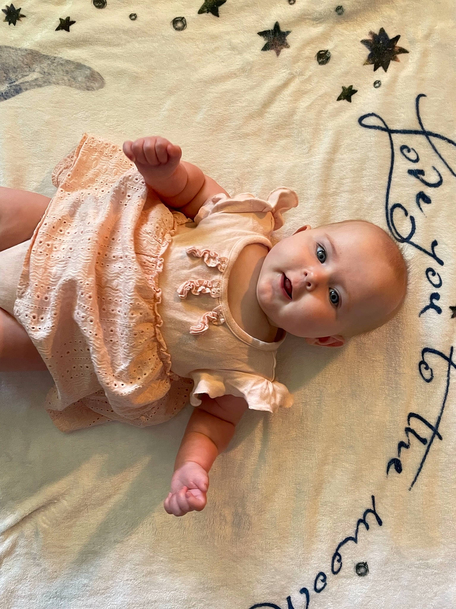 Lyra is registered to the contest to win money with this photo: baby, baby_toddler_clothing, barefoot, beach, cheek, child, flooring, font, foot, fun, happy, linens, pattern, person, photo_caption, skin, sleeve, smile, thumb, toddler