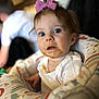 baby, child, high_chair, food, messy_face, purple_bow, blue_eyes, white_clothing, indoor, person, infant, curious, cute, mess, feeding_time, soft_focus, portrait, young_child, seated, colorful