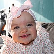 Lyssana a rejoint le concours — aidez-le/la à gagner de superbes lots ! baby, bow, cheeks, child, close_up, couch, dress, eyes, floral_print, happy, headband, indoor, infant, pattern, pillow, portrait, smile, sofa, soft_lighting, teeth