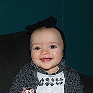 Lyssana a rejoint le concours — aidez-le/la à gagner de superbes lots ! baby, black_bow, cardigan, child, closeup, couch, cute, dark_background, face, flower_pattern, happy, headband, indoor, infant, portrait, seated, smiling, teal_wall, white_shirt, young_child