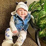Zelda joined the competition — help win amazing prizes! baby, child, smile, hat, denim_vest, floral_pants, shoes, chair, leopard_print, indoor, plant, greenery, cute, portrait, seated, happy, face, clothing, infant, cozy