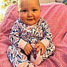 baby, child, smiling, onesie, pink_blanket, indoor, cute, infant, sitting, hand, foot, patterned_clothing, cushion, animal_print, cozy, portrait, happy, soft_texture, person, face