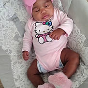 Amoura is registered to the contest to win money with this photo: baby, infant, sleeping, pink_bow, hello_kitty, onesie, fluffy_slippers, baby_seat, cushion, indoor, wood_floor, cute, child, soft_toys, toddler, headwear, footwear, relaxing, adorable, resting