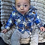 baby, child, plaid_shirt, gray_pants, blanket, soft_texture, seated, indoor, cute, curious, face, head, hands, legs, cozy, casual_clothing, infant, portrait, comfortable, cute_expression