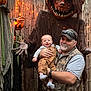 baby, man, pumpkin, halloween, costume, scary, outdoor, decoration, smiling, face, child, adult, festive, orange, lights, wooden_fence, vest, socks, cap, overalls