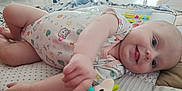 Aïvy a rejoint le concours — aidez-le/la à gagner de superbes lots ! baby, child, clothing, colorful, cute, face, floor, foot, hand, happy, indoor, infant, lying_down, patterned, playful, quilt, smiling, soft_light, toy, young