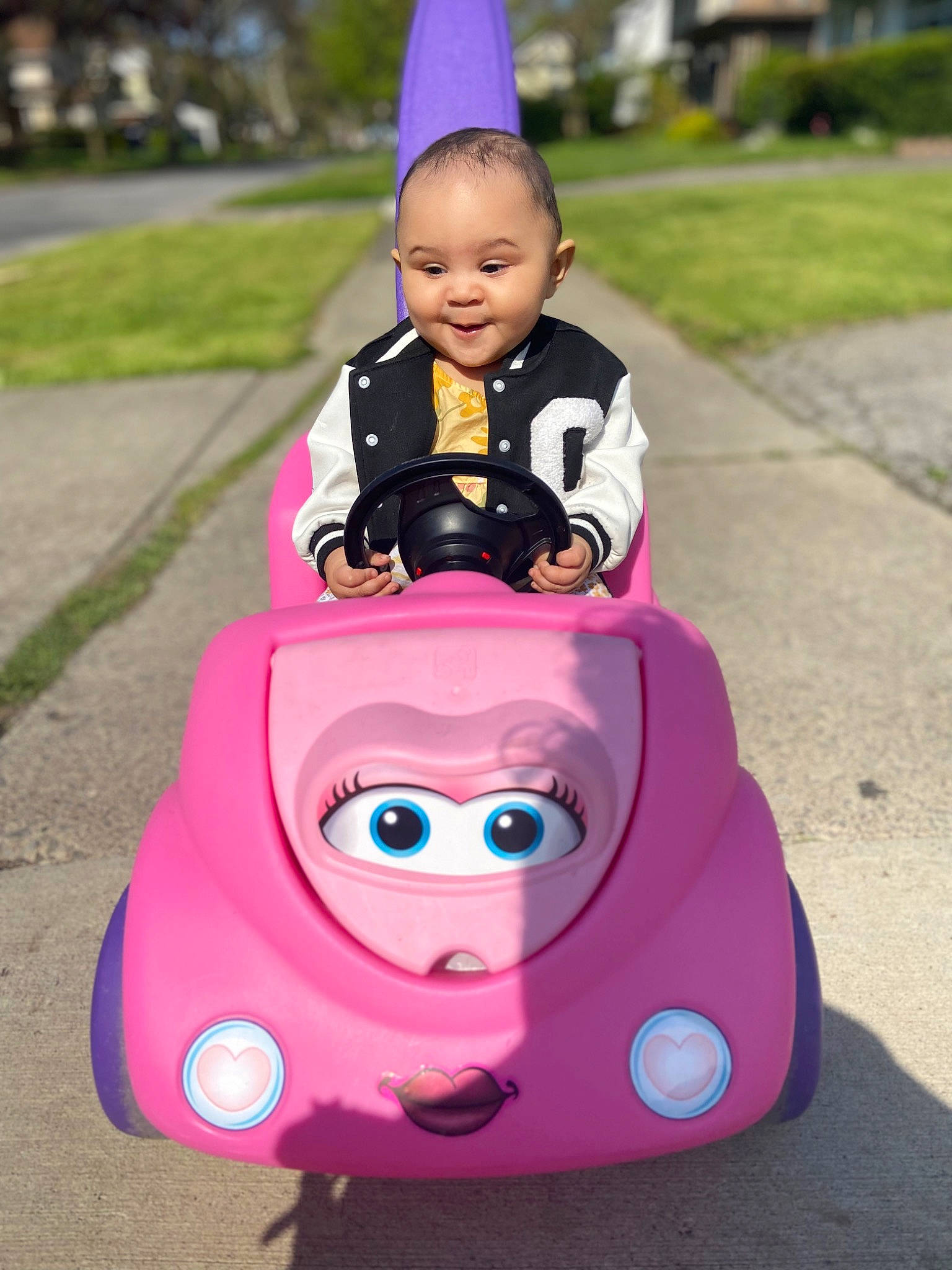 Amiyah is registered to the contest to win money with this photo: automotive_design, automotive_exterior, automotive_lighting, automotive_wheel_system, baby, baby_carriage, bumper, grass, happy, magenta, motor_vehicle, person, pink, purple, recreation, red, riding_toy, smile, toddler, toy