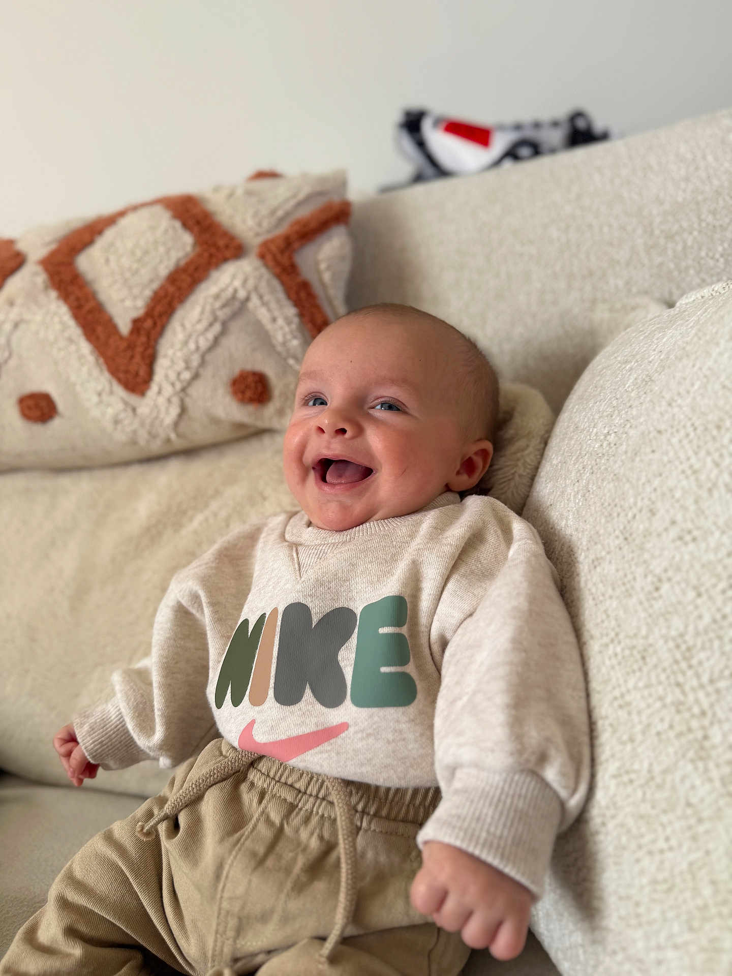 Mylan a rejoint le concours — aidez-le/la à gagner de superbes lots ! baby, smiling, sweatshirt, nike, pants, couch, pillows, happy, indoors, child, person, clothing, seated, cute, infant, cozy, relaxed, portrait, home, casual