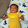 Tyler joined the competition — help win amazing prizes! baby, smiling, yellow_onesie, mittens, blanket, dinosaur_pattern, couch, happy, infant, child, lying_down, cute, indoors, face, expression, comfort, plush, clothing, toy_clip, portrait
