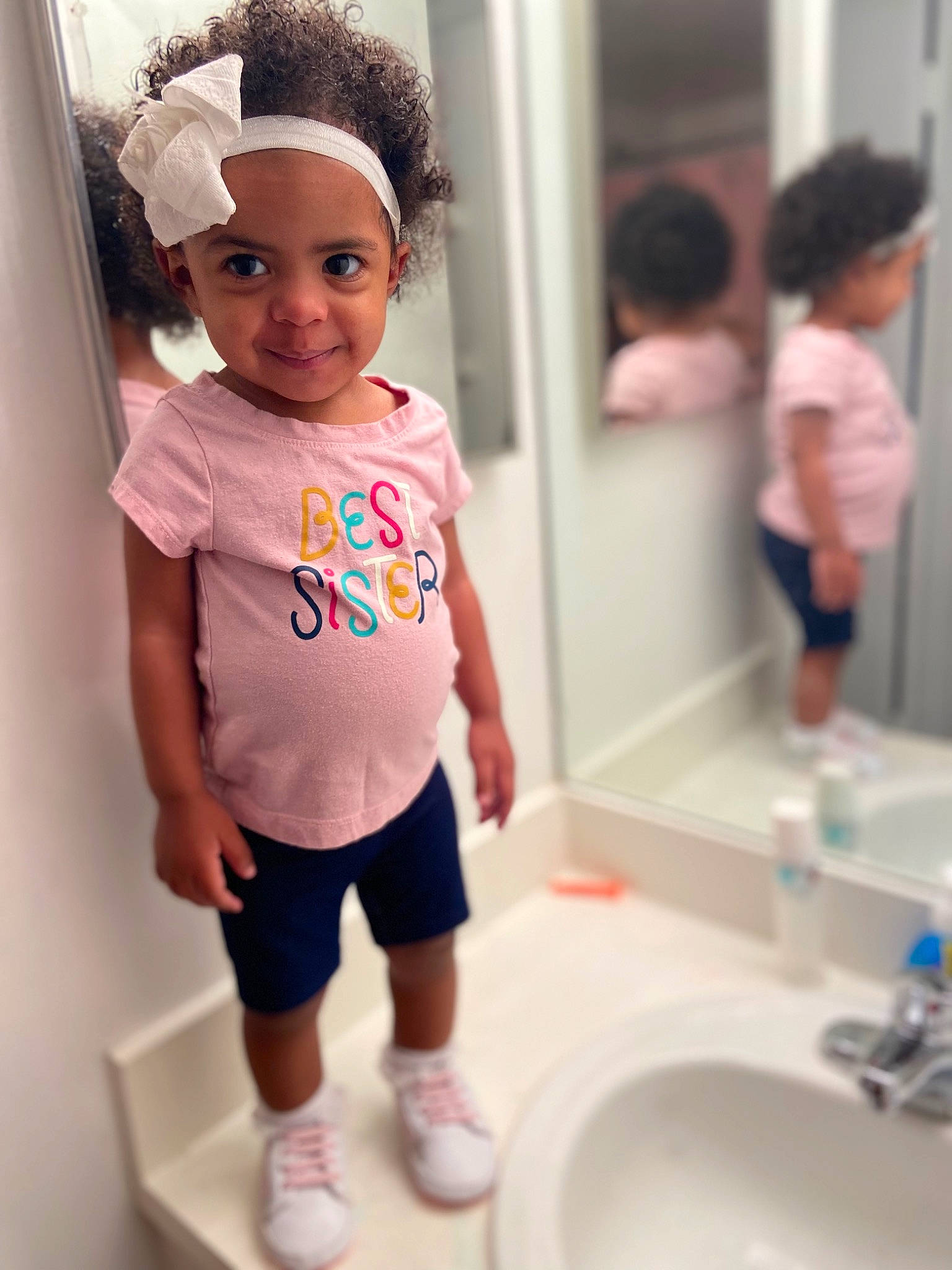 Angela is registered to the contest to win money with this photo: baby_toddler_clothing, bathroom, beauty, cap, child, fashion_design, happy, joy, mirror, person, photograph, pink, plumbing_fixture, purple, shorts, sink, sleeve, smile, t_shirt, tap