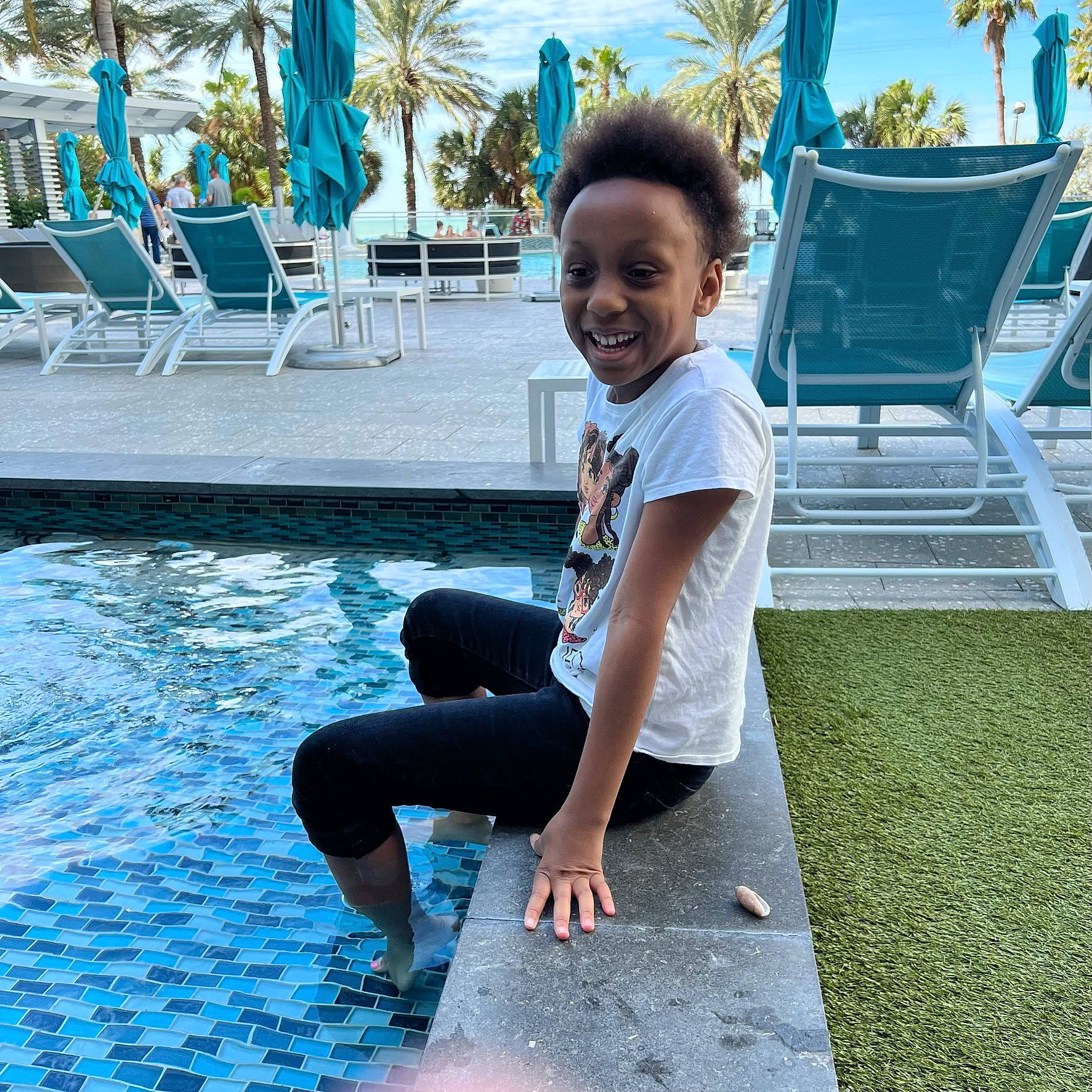 Iris is registered to the contest to win money with this photo: barefoot, blue, chair, electric_blue, flooring, foot, fun, grass, happy, human_leg, joy, knee, leisure, outdoor_furniture, person, recreation, sitting, smile, thigh, toddler