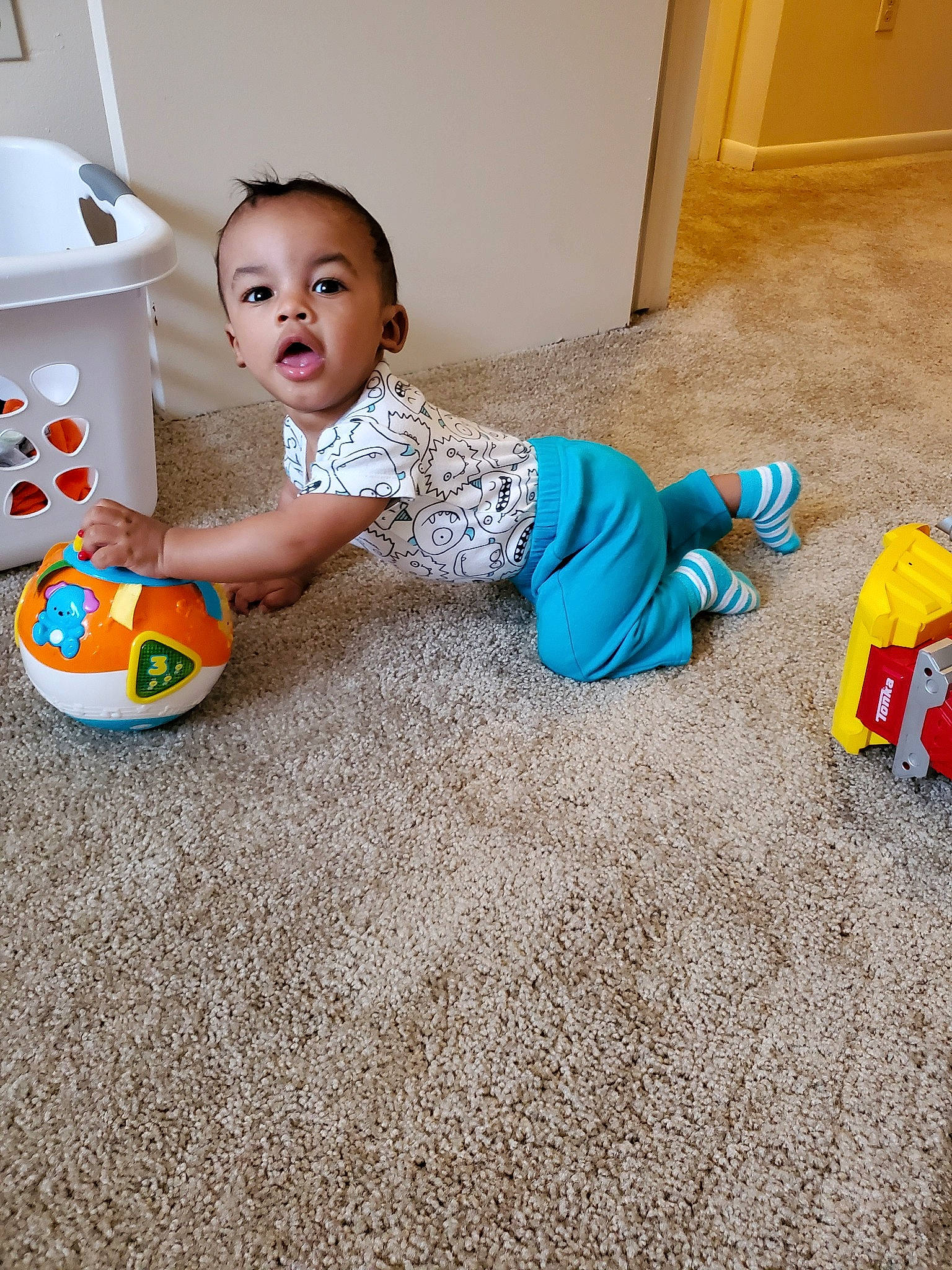 Brysen is registered to the contest to win money with this photo: baby, baby_playing_with_toys, ball, child, crawling, floor, flooring, pajamas, person, play, room, sitting, toddler, toy