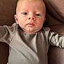 Marshall is registered to the contest to win money with this photo: baby, infant, face, portrait, person, clothing, cushion, brown, grey, eyes, head, skin, young_child, lying_down, indoors, close_up, expression, cute, soft_texture, comfortable