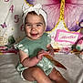 baby, child, smiling, headband, bow, dress, green_dress, sitting, blanket, soft_texture, butterfly, colorful_background, milestone_photo, numbers, months, card, white_sneakers, cute, happy, indoor