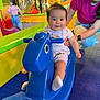 adult, baby, blue, child, clothing, colorful, floor, fun, happy, indoor, person, pink, play, play_area, playground, rocking_horse, smile, supporting_hand, toddler, toy