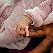 Amara Nuna a rejoint le concours — aidez-le/la à gagner de superbes lots ! baby, infant, newborn, tiny_fingers, hand, adult_hand, holding, finger, pink_blanket, blanket, soft_fabric, cozy, close_up, skin, palm, sleeve, clothing, bonding, family, warmth