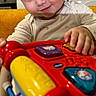 Demir a rejoint le concours — aidez-le/la à gagner de superbes lots ! toddler, child, toy, indoor, couch, yellow, play, smile, blue_eyes, face, hand, clothing, kitchen, appliance, microwave, cabinet, furniture, happy, person, portrait