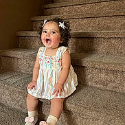 Alaia is registered to the contest to win money with this photo: toddler, child, smiling, sitting, stairs, carpet, dress, curly_hair, bows, pink_slippers, socks, indoor, happy, cute, young_child, person, fashion, footwear, playful, portrait