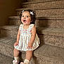 toddler, child, smiling, sitting, stairs, carpet, dress, curly_hair, bows, pink_slippers, socks, indoor, happy, cute, young_child, person, fashion, footwear, playful, portrait