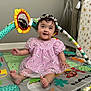 baby, child, girl, purple_dress, floral, headband, daisy, play_mat, mirror_toy, colorful, sitting, smiling, indoor, lamp, curly_hair, cute, happy, toys, floor, portrait