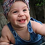 baby, child, smiling, headband, denim_overalls, happy, face, skin, arm, fingers, outdoor, nature, greenery, portrait, cute, infant, playful, expression, closeup, person