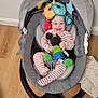 baby, baby_rocker, striped_pajamas, mickey_mouse_toy, plush_toy, hanging_toys, indoor, wooden_floor, blanket, baby_items, toy_phone, smiling, child, seat, happy, infant, floor, playful, cute, cozy