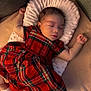 Heaven is registered to the contest to win money with this photo: baby, sleeping, dress, red, plaid, cushion, sock, infant, peaceful, soft, cozy, child, cute, resting, indoors, fabric, textured, person, small, adorable