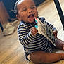 Kazrin joined the competition — help win amazing prizes! baby, child, smiling, happy, striped_clothing, sitting, indoors, wooden_floor, holding_object, package, metal_clips, cute, infant, person, joyful, playful, diaper, young_child, portrait, face