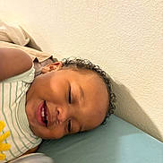 Kazrin is registered to the contest to win money with this photo: toddler, child, smiling, bed, striped_clothing, yellow_flower, curly_hair, face, happy, indoor, pillow, light_blue, wall, person, young_child, cute, skin, head, teeth, relaxed