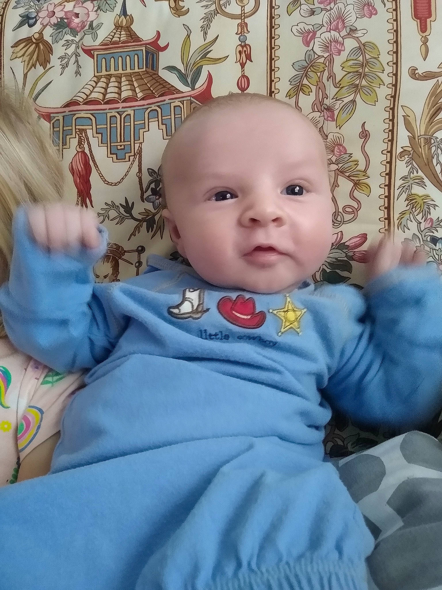 Kyle is registered to the contest to win money with this photo: baby, baby_products, baby_toddler_clothing, cheek, child, comfort, electric_blue, fun, happy, linens, person, pink, product, room, sitting, skin, sleeve, t_shirt, textile, toddler