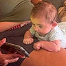 baby, infant, child, portrait, face, curious, lying_down, tummy_time, smartphone, phone, adult, lap, couch, indoor, home, short_sleeves, light_clothing, close_up, family, technology