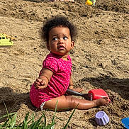 Lila participe au concours pour gagner de l'argent avec cette photo : toddler, child, sand, beach, shovel, toy, play, outdoor, grass, water, person, summer, sunlight, sitting, curly_hair, pink_clothing, barefoot, sandcastle, playtime, nature