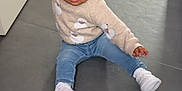 Lila participe au concours pour gagner de l'argent avec cette photo : toddler, child, indoor, floor, tile_floor, sweater, jeans, white_shoes, hair_tied, cute, balancing, sitting, young_child, casual_clothing, portrait, person, baby, expression, candid, home