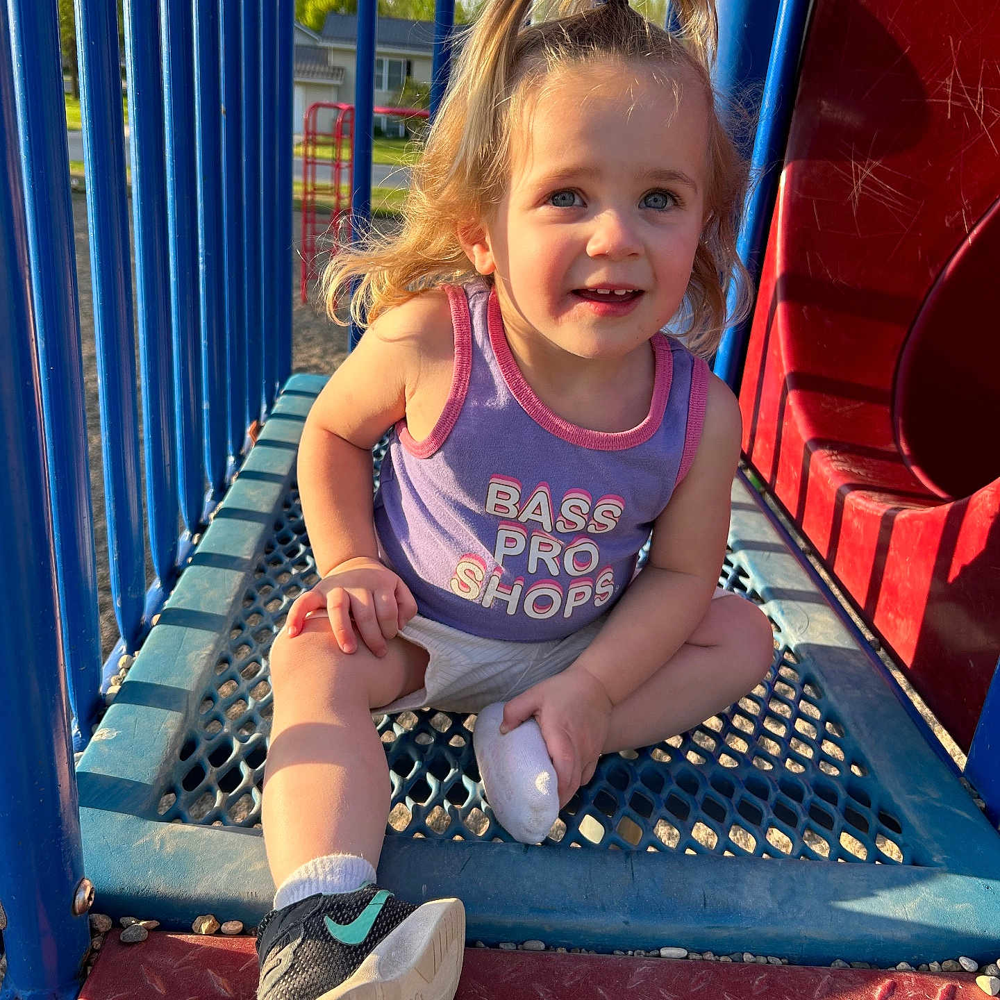 Layla is registered to the contest to win money with this photo: blond_hair, blue_bars, casual_clothing, child, cute, happy, metal_platform, outdoor, person, playground, playground_equipment, pony_tail, purple_tank_top, red_slide, smiling, sneaker, sock, summer, sunlight, toddler