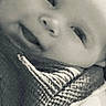 Charlie is registered to the contest to win money with this photo: baby, infant, child, portrait, face, smiling, eyes, nose, cheeks, blanket, wrap, patterned_fabric, clothing, pacifier, close_up, black_and_white, grayscale, cozy, indoors, photography