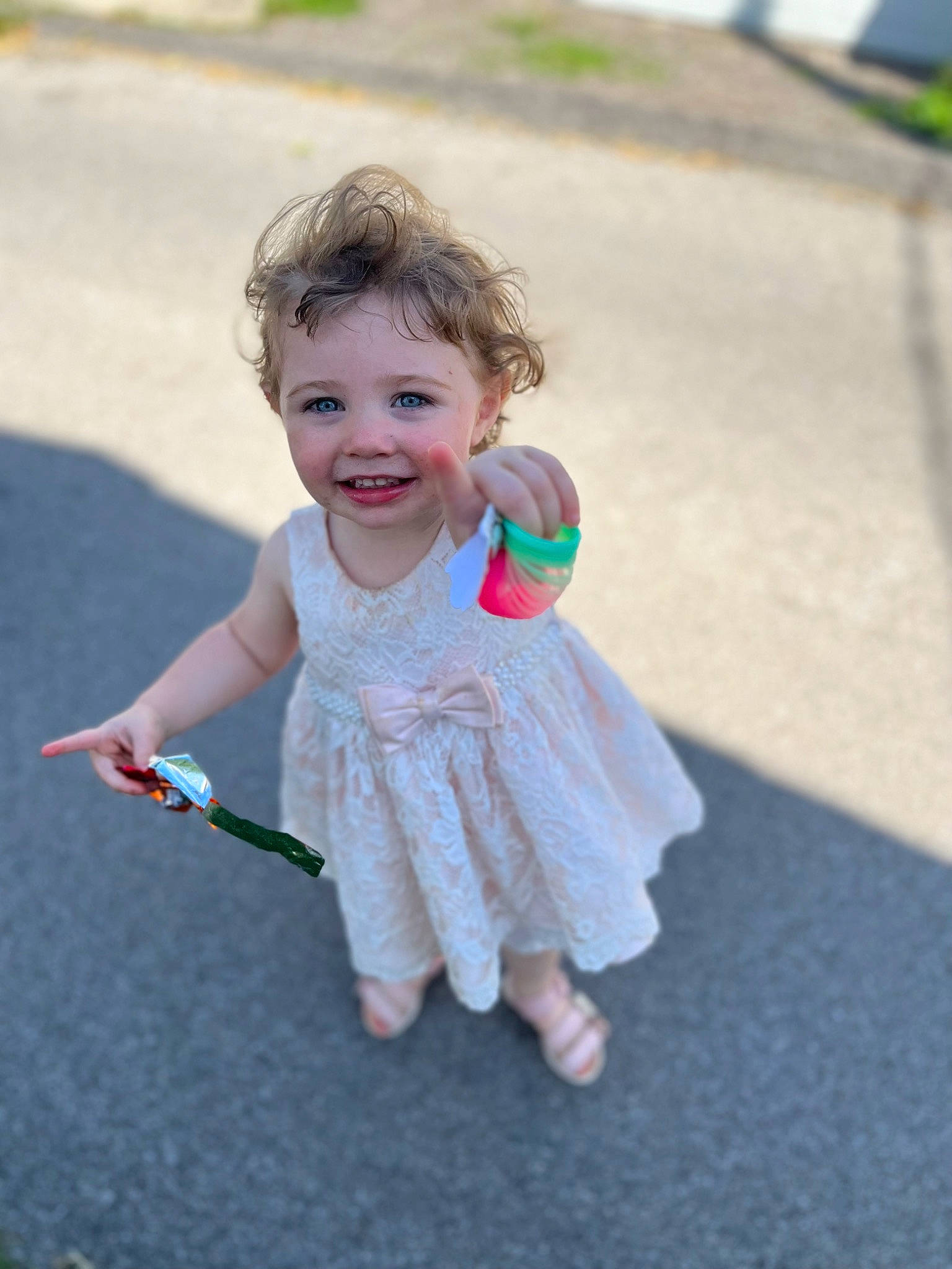 Alice is registered to the contest to win money with this photo: asphalt, dress, facial_expression, fun, gesture, grass, hair, happy, head, joint, joy, leisure, mammal, person, plant, public_space, recreation, skin, smile, toddler