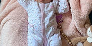 Anna participe au concours pour gagner de l'argent avec cette photo : baby, infant, onesie, blanket, pink, plush_toy, pacifier_clip, cute, sleepwear, child, soft, cozy, lying_down, furniture, indoor, portrait, face, raised_arms, toy, comfort