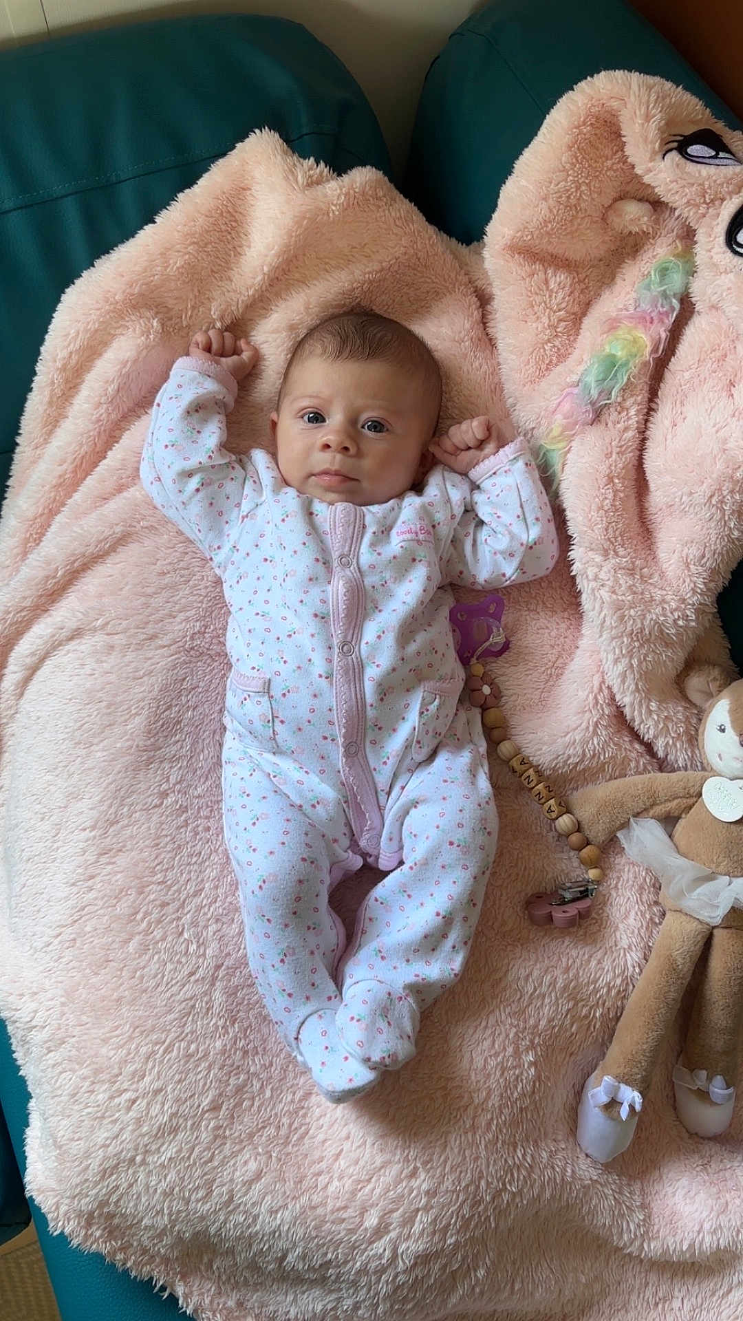 Anna participe au concours pour gagner de l'argent avec cette photo : baby, infant, onesie, blanket, pink, plush_toy, pacifier_clip, cute, sleepwear, child, soft, cozy, lying_down, furniture, indoor, portrait, face, raised_arms, toy, comfort
