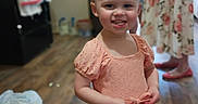 Dalilah is registered to the contest to win money with this photo: toddler, child, smile, peach_dress, floor, wooden_floor, indoor, kitchen, person, woman, adult, floral_dress, shoes, happy, portrait, family, home, background_blur, standing, candid