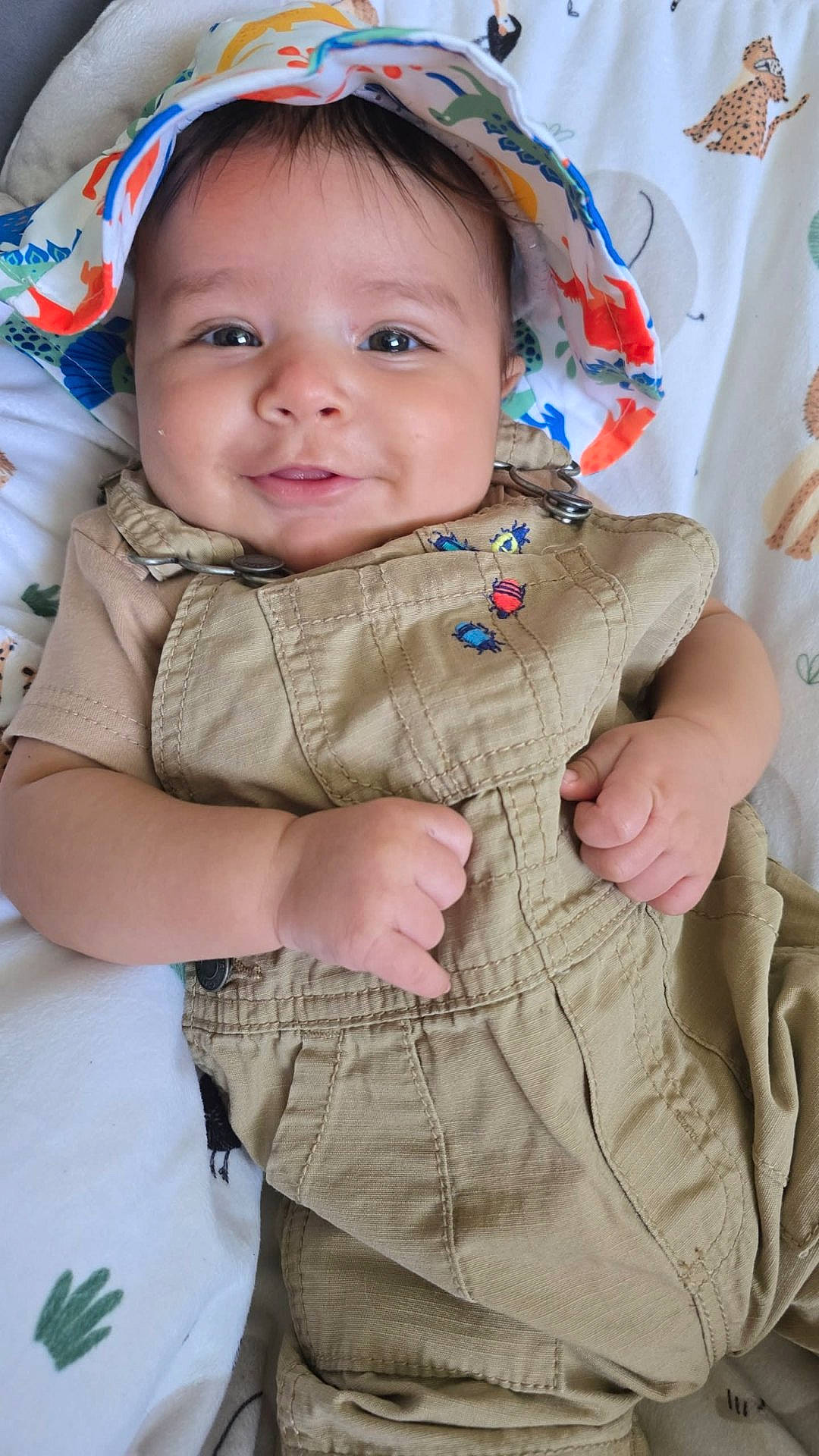 Oliver joined the competition — help win amazing prizes! animal_print, baby, blanket, cheeks, child, closeup, clothing, cute, face, hand, happy, hat, indoors, infant, lying_down, overalls, person, portrait, smiling, toddler