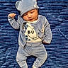 baby, child, blue_outfit, hat, bear_ears, blanket, plush, soft_texture, lying_down, cute, infant, clothing, socks, portrait, face, smile, indoor, person, newborn, comfortable