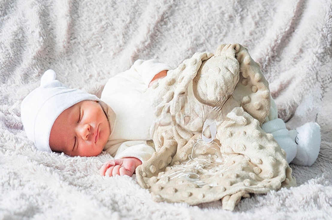 Noham participe au concours pour gagner de l'argent avec cette photo : baby, newborn, sleeping_baby, infant, blanket, plush_blanket, soft_texture, cozy, hat, white_hat, swaddle, hand, closed_eyes, peaceful, portrait, bed, comfort, beige, nursery, security_blanket