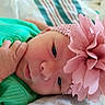 Rylee is registered to the contest to win money with this photo: baby, infant, child, portrait, close_up, face, eyes, hand, green_outfit, pink_flower, headband, lying_down, indoor, blanket, bed, soft_lighting, colorful, cute, looking_at_camera, photography