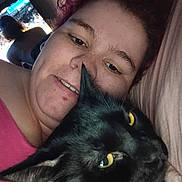 Negrita joined the competition — help win amazing prizes! black_cat, cat, pet, person, selfie, close_up, yellow_eyes, indoor, bedroom, pillow, bedding, hair, whiskers, ear, television, tv_screen, background_figure, cozy, portrait, cuddling