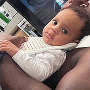 Leon joined the competition — help win amazing prizes! adult, arm, baby, child, closeup, clothing, eyes, face, furniture, hand, holding, home, indoor, person, portrait, sitting, skin, striped_bib, television, white_shirt