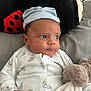 baby, infant, plush_toy, cap, onesie, animal_print, pillow, ladybug, bed, blanket, hand, face, eyes, cute, soft_toy, child, indoor, resting, portrait, newborn
