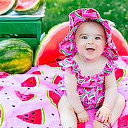 Valentina is registered to the contest to win money with this photo: baby, blanket, child, colorful, cute, food, fruit, grass, green, happy, hat, nature, outdoor, patterned_clothing, pink, playful, sitting, smiling, summer, watermelon